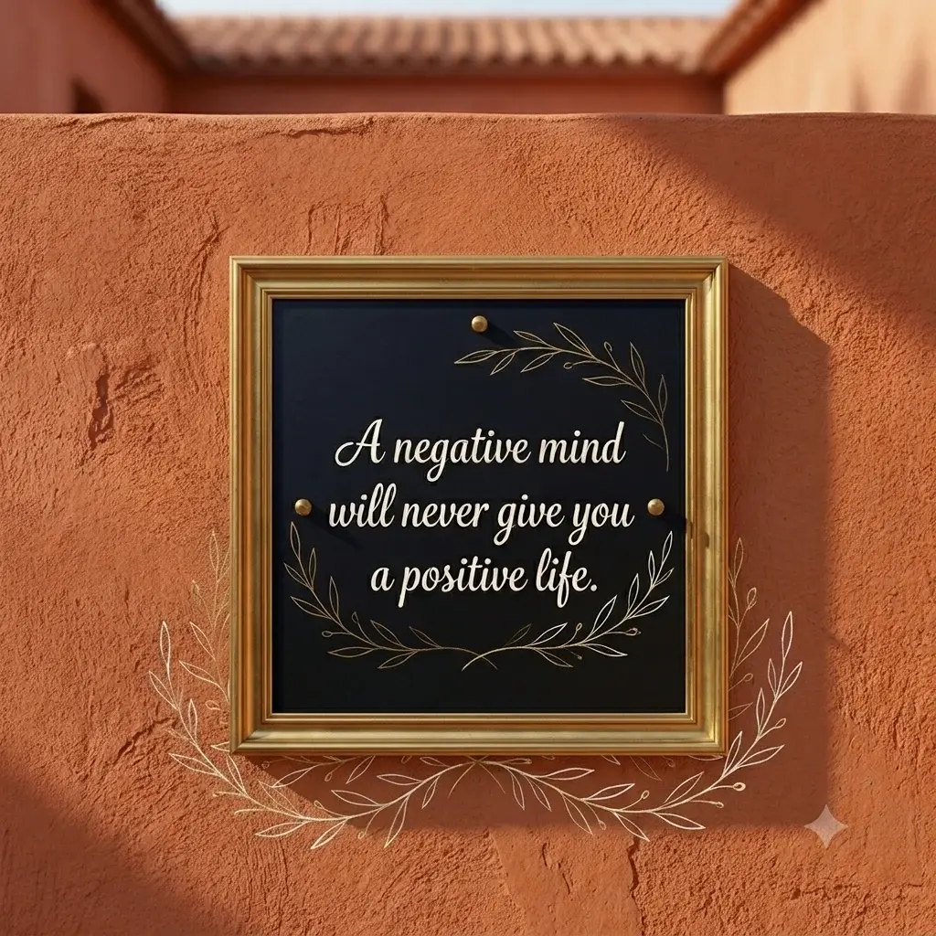 Framed black slate board featuring the inspirational quote 'A negative mind will never give you a positive life' with gold leaf accents on a terracotta wall background